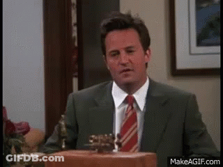 A Man In A Suit And Tie Is Standing In Front Of A Podium In A Room . GIF