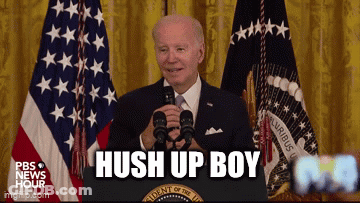A Man In A Suit And Tie Is Standing In Front Of A Podium With The Words Hush Up Boy On It GIF