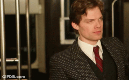 A Man In A Suit And Tie Is Standing In Front Of A Railing GIF