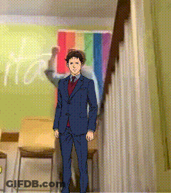 A Man In A Suit And Tie Is Standing In Front Of A Rainbow Flag In A Room GIF