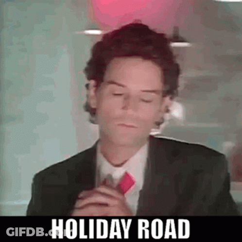 A Man In A Suit And Tie Is Standing In Front Of A Red Light . GIF