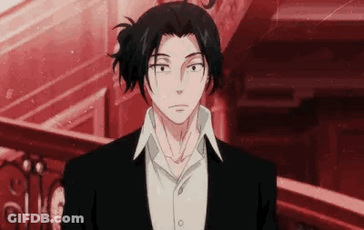 A Man In A Suit And Tie Is Standing In Front Of A Red Wall . GIF