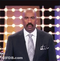 A Man In A Suit And Tie Is Standing In Front Of A Row Of Lights . GIF