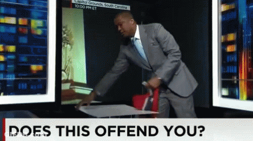 A Man In A Suit And Tie Is Standing In Front Of A Screen That Says Does This Offend You GIF
