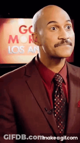 A Man In A Suit And Tie Is Standing In Front Of A Screen That Says Go Monday Los Angeles GIF