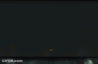 A Man In A Suit And Tie Is Standing In Front Of A Screen With The Letter D On It GIF