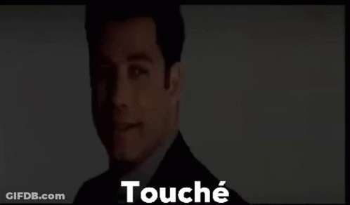 A Man In A Suit And Tie Is Standing In Front Of A Screen With The Words Touché Written On It . GIF