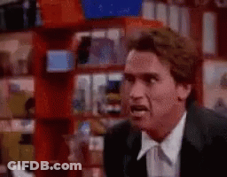 A Man In A Suit And Tie Is Standing In Front Of A Shelf In A Store . GIF