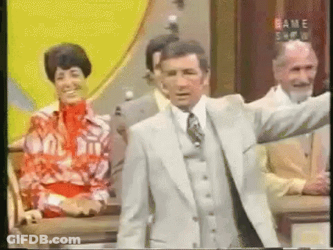 A Man In A Suit And Tie Is Standing In Front Of A Sign That Says " Game Show " GIF