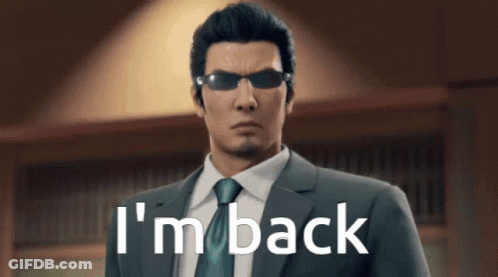 A Man In A Suit And Tie Is Standing In Front Of A Sign That Says I 'M Back GIF
