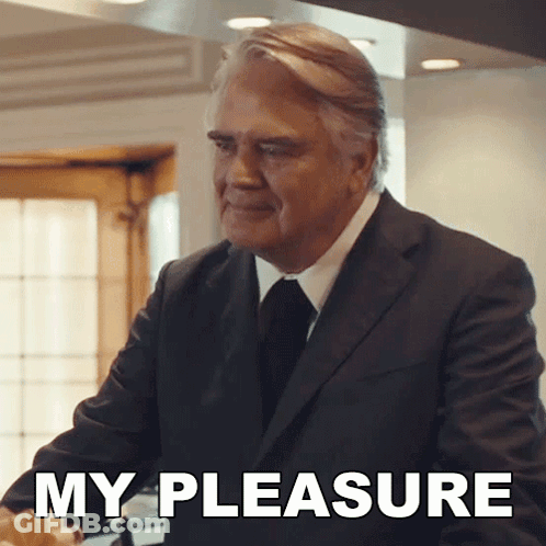 A Man In A Suit And Tie Is Standing In Front Of A Sign That Says " My Pleasure " GIF