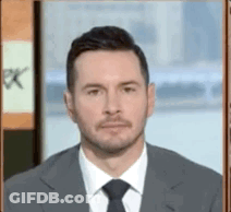 A Man In A Suit And Tie Is Standing In Front Of A Sign That Says Pk GIF