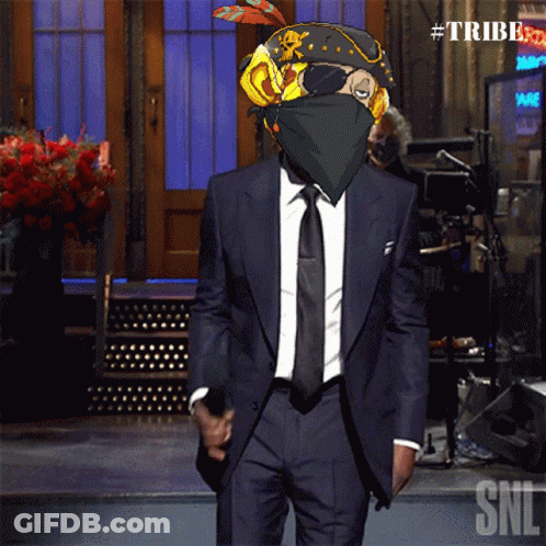 A Man In A Suit And Tie Is Standing In Front Of A Sign That Says Tribe GIF