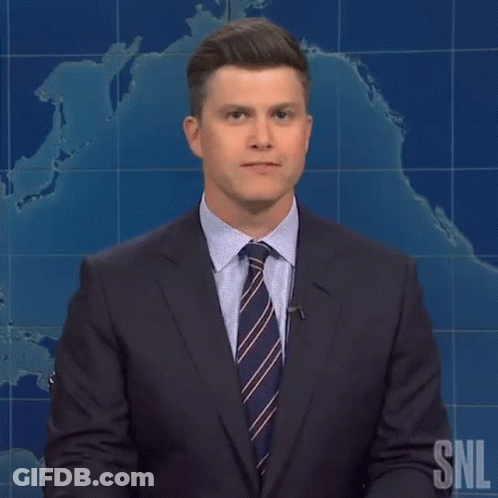 A Man In A Suit And Tie Is Standing In Front Of A Snl Sign GIF