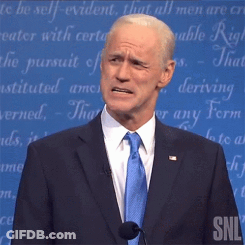 A Man In A Suit And Tie Is Standing In Front Of A Snl Sign GIF