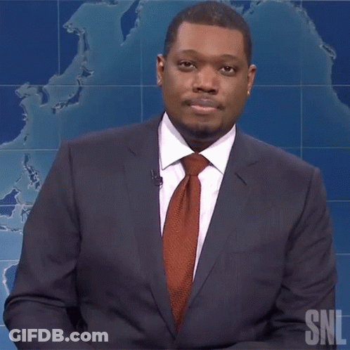 A Man In A Suit And Tie Is Standing In Front Of A Snl Sign GIF