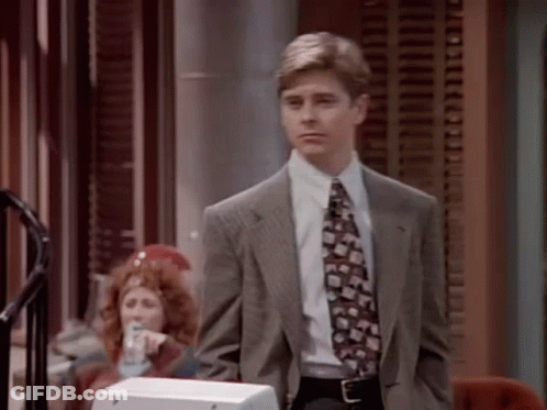A Man In A Suit And Tie Is Standing In Front Of A Telephone GIF