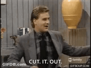A Man In A Suit And Tie Is Standing In Front Of A Vase . GIF