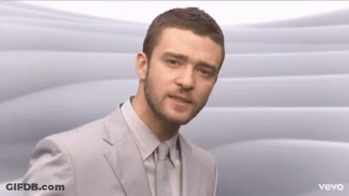 A Man In A Suit And Tie Is Standing In Front Of A Vevo Logo GIF