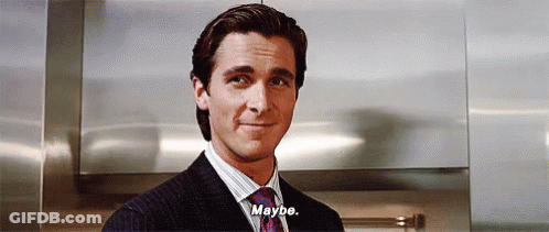 A Man In A Suit And Tie Is Standing In Front Of A Wall And Saying `` Maybe '' . GIF