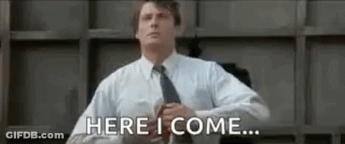 A Man In A Suit And Tie Is Standing In Front Of A Wall And Says `` Here I Come '' . GIF