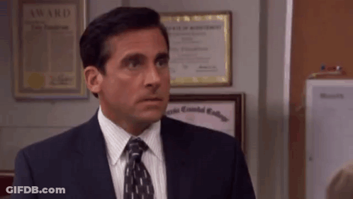 A Man In A Suit And Tie Is Standing In Front Of A Wall . GIF