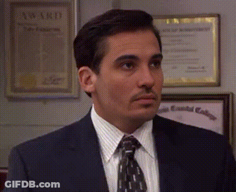 A Man In A Suit And Tie Is Standing In Front Of A Wall With A Certificate Hanging On It . GIF