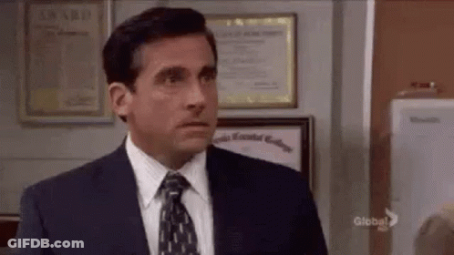 A Man In A Suit And Tie Is Standing In Front Of A Wall With A Certificate On It . GIF