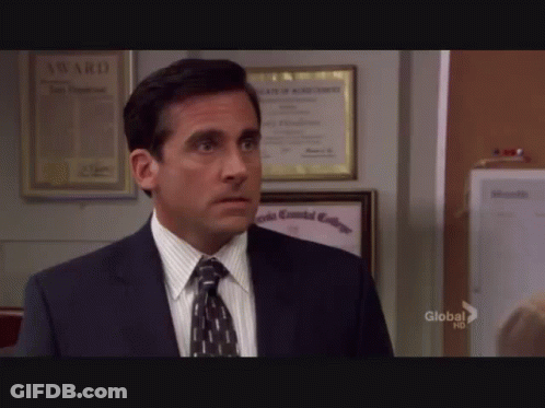 A Man In A Suit And Tie Is Standing In Front Of A Wall With A Framed Certificate That Says Award On It GIF