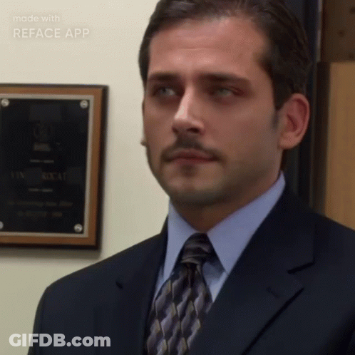 A Man In A Suit And Tie Is Standing In Front Of A Wall With A Plaque On It That Says Reface App On It GIF