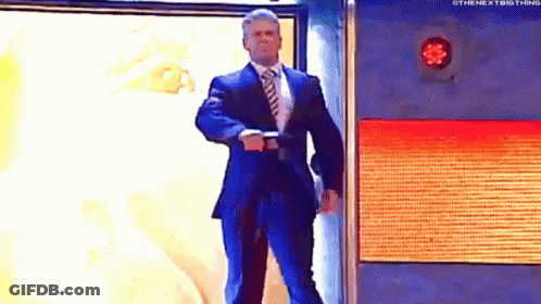 A Man In A Suit And Tie Is Standing In Front Of A Wall With A Red Light On It . GIF