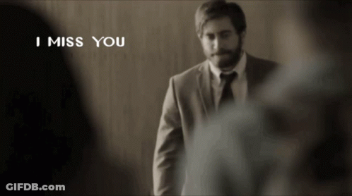 A Man In A Suit And Tie Is Standing In Front Of A Wall With The Words I Miss You Above Him GIF