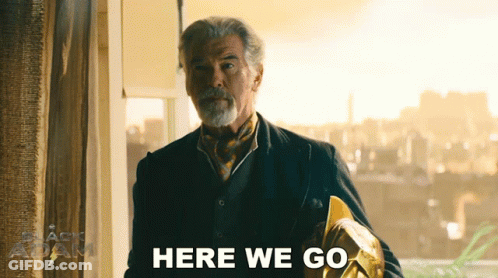 A Man In A Suit And Tie Is Standing In Front Of A Window And Says Here We Go GIF
