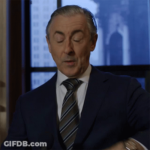 A Man In A Suit And Tie Is Standing In Front Of A Window With His Eyes Closed GIF