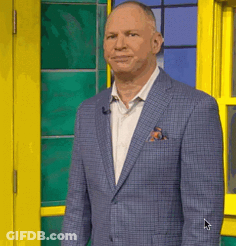 A Man In A Suit And Tie Is Standing In Front Of A Yellow Door And Window . GIF