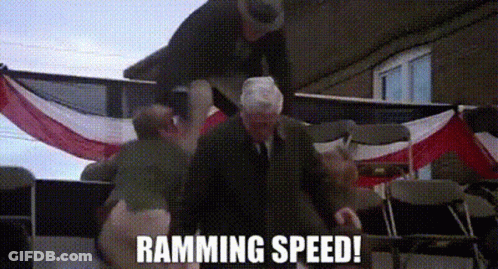 A Man In A Suit And Tie Is Standing In Front Of An American Flag With The Words Ramming Speed Written On It . GIF