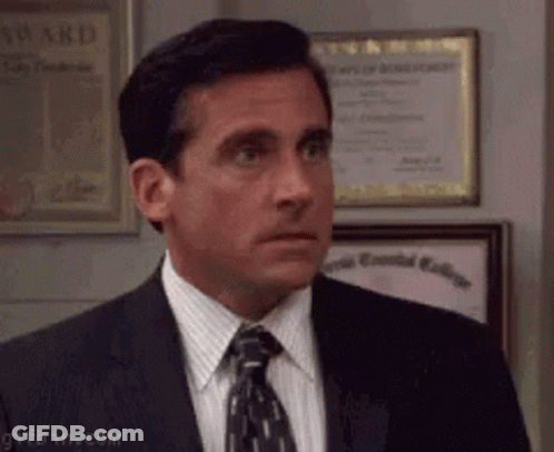A Man In A Suit And Tie Is Standing In Front Of Framed Awards . GIF