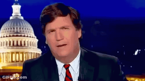 A Man In A Suit And Tie Is Standing In Front Of The Capitol Building At Night . GIF