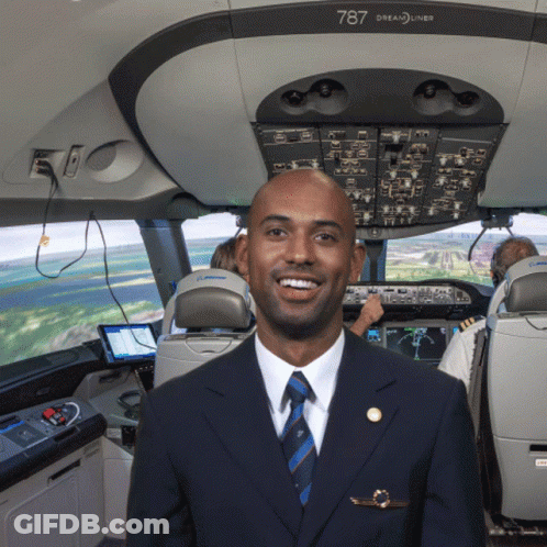 A Man In A Suit And Tie Is Standing In The Cockpit Of A 787 Dreamliner GIF