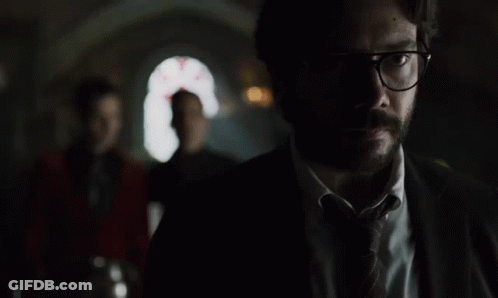 A Man In A Suit And Tie Is Standing In The Dark GIF