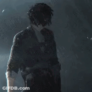 A Man In A Suit And Tie Is Standing In The Dark Holding A Gun . GIF