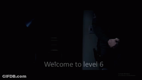 A Man In A Suit And Tie Is Standing In The Dark With The Words Welcome To Level 6 Below Him GIF
