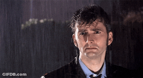 A Man In A Suit And Tie Is Standing In The Rain With His Eyes Closed GIF