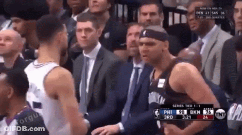 A Man In A Suit And Tie Is Standing Next To A Basketball Player GIF