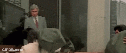 A Man In A Suit And Tie Is Standing Next To A Group Of People In A Room . GIF