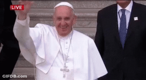 A Man In A Suit And Tie Is Standing Next To A Man In A White Robe Who Is Waving . GIF