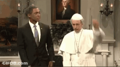 A Man In A Suit And Tie Is Standing Next To A Pope In A Room . GIF