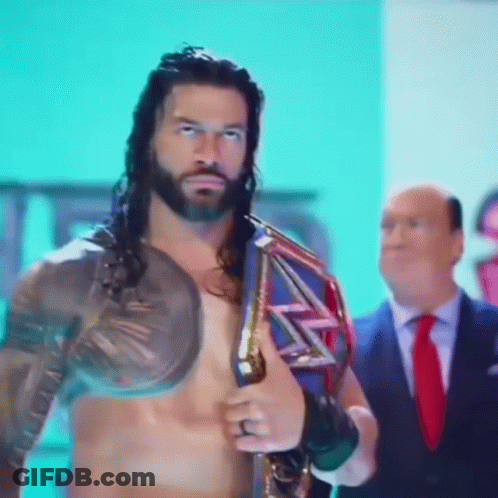 A Man In A Suit And Tie Is Standing Next To A Shirtless Wrestler Holding A Wrestling Championship Belt GIF