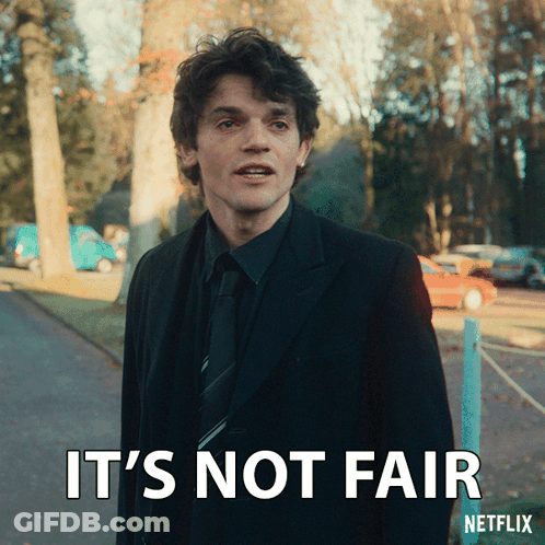 A Man In A Suit And Tie Is Standing Next To A Sign That Says " It 'S Not Fair " GIF