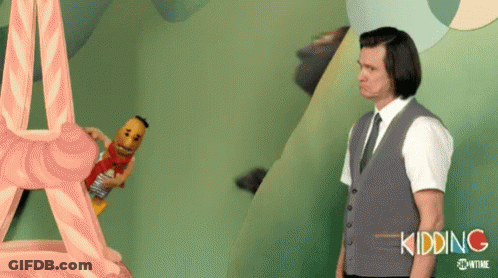 A Man In A Suit And Tie Is Standing Next To A Stuffed Animal That Says Kidding On It . GIF